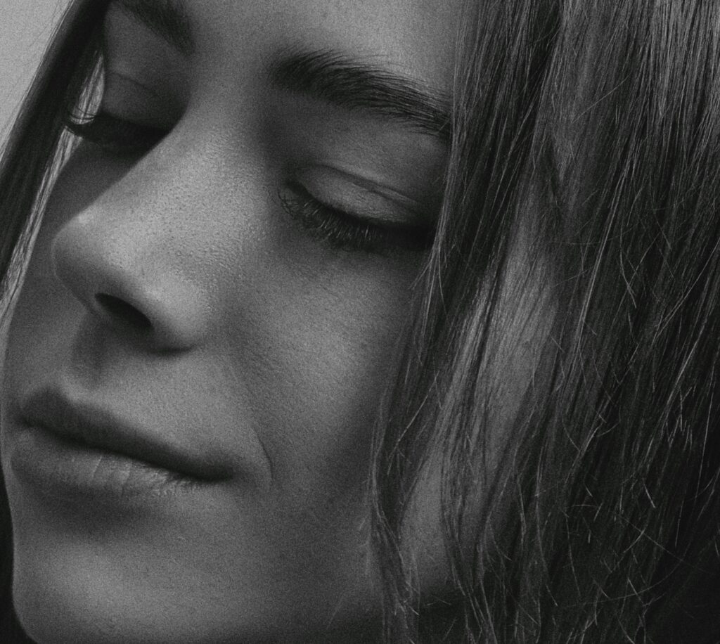 Elegant black and white close-up portrait of a woman with eyes closed, highlighting serene expression.