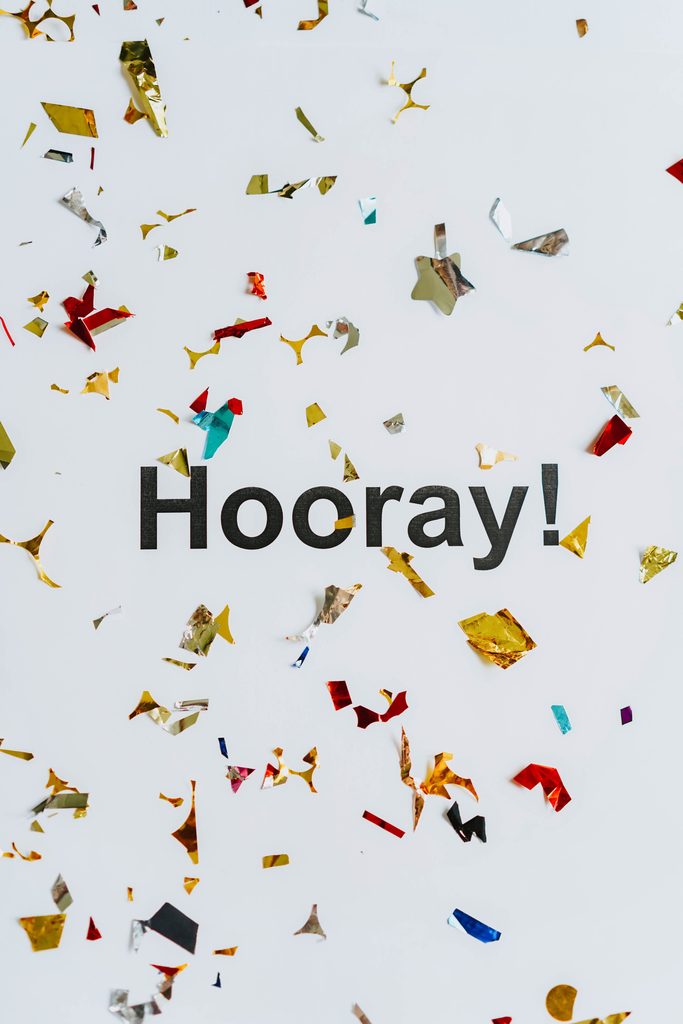 Vibrant confetti falling around the word 'Hooray!' on a white background, celebrating success and happiness.